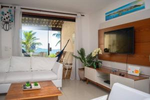 a living room with a white couch and a tv at Casa Frente para o Mar em Búzios, Geribá Beach! in Búzios
