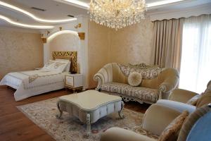 een woonkamer met een bank, een bed en een kroonluchter bij Hotel Eiffel in Tirana