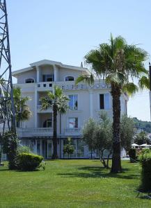 een wit gebouw met palmbomen ervoor bij Hotel Eiffel in Tirana