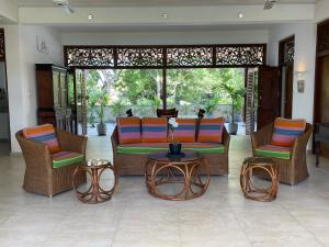 ein Wohnzimmer mit Stühlen, einem Sofa und einem Tisch in der Unterkunft Khomba Lodge in Tangalle