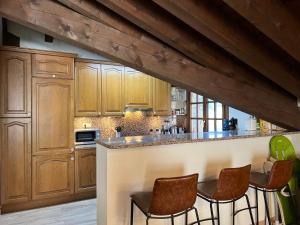 a kitchen with wooden cabinets and bar stools at Cases de Canillo-Casa Sant Joan de Caselles in Canillo