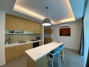 a kitchen with a white counter and blue stools at Tropical 1bedroom Apartment in Kamala Beach