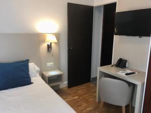 a bedroom with a bed and a desk and a phone at Hotel Lauria in Tarragona
