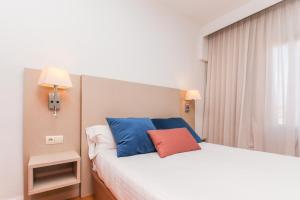 a bedroom with a bed with blue and red pillows at Hotel Lauria in Tarragona