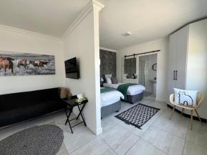 ein Schlafzimmer mit 2 Betten und ein Wohnzimmer mit einem Sofa in der Unterkunft On the Main in Walvis Bay