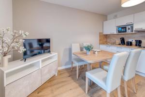 cocina y comedor con mesa y TV en OVELIA Bourg-en-Bresse - Les Jardins de Voltaire en Bourg-en-Bresse