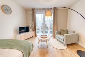 1 dormitorio con 1 cama, 1 silla y TV en OVELIA Bourg-en-Bresse - Les Jardins de Voltaire en Bourg-en-Bresse