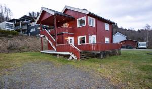 a red house with a large deck on a yard at Lillehammer Camping in Lillehammer