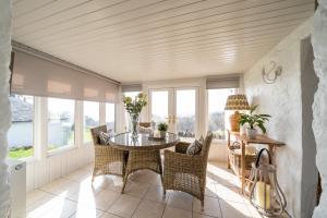 een eetkamer met een tafel, stoelen en ramen bij Nether Glenny Farm in Stirling