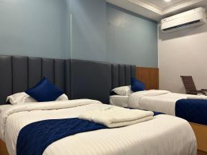 a hotel room with three beds with blue pillows at KKM Highlands in Kurnool