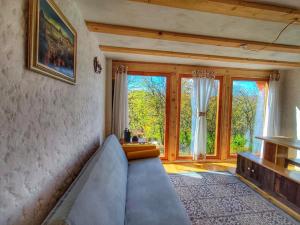a living room with a couch and some windows at La sat - Blândă Mărie in Bertea