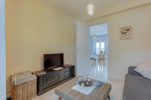a living room with a couch and a tv and a table at Les Ebihens in Saint-Benoît-des-Ondes