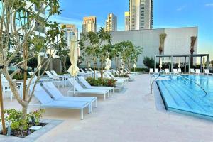 uma piscina com espreguiçadeiras brancas e uma piscina em Luxury Dubai Creek Balcony & View em Dubai