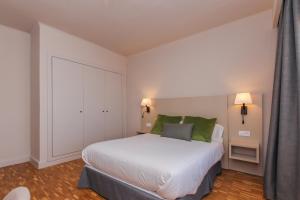 a bedroom with a large white bed with green pillows at Hotel Lauria in Tarragona