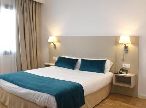 a hotel room with a large bed with blue pillows at Hotel Lauria in Tarragona