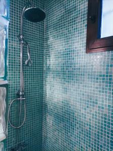 y baño con ducha de azulejos verdes y cabezal de ducha. en alojamiento rural EL METGE, en Penàguila