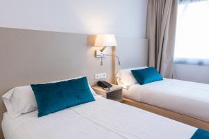 a hotel room with two beds with blue pillows at Hotel Lauria in Tarragona