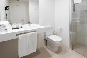 a white bathroom with a toilet and a sink at Hotel Lauria in Tarragona