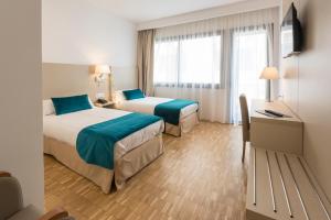 a hotel room with two beds and a desk at Hotel Lauria in Tarragona