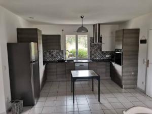 a kitchen with a table and a stainless steel refrigerator at La Maison du Bagas, 7pers in Vielmur