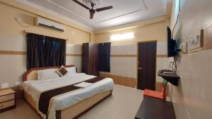a bedroom with a bed and a flat screen tv at Goroomgo Star Inn Puri in Puri