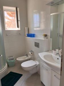 La salle de bains blanche est pourvue de toilettes et d'un lavabo. dans l'établissement Apartments Paska Preko, à Preko