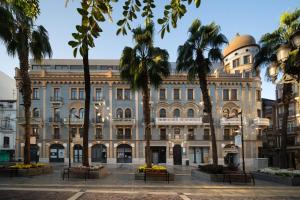 un edificio con palmeras delante en Hostal Antiguo Palacio Hotel París, en Huelva