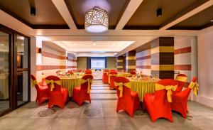 a banquet hall with red chairs and tables and a screen at Udaan Woodberry Hotel & Spa in Gangtok