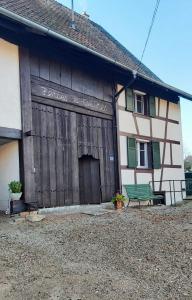 a building with a wooden door and a bench in front at Herbes et collines in Winkel