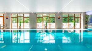 a large swimming pool with blue water and windows at Apartamenty Good Time - Stone Hill IV in Szklarska Poręba