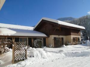 ein schneebedecktes Haus mit einem Holztor in der Unterkunft Gîte Tournette in Thônes