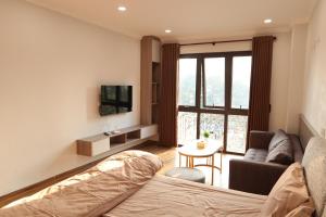 - un salon avec un lit, un canapé et une télévision dans l'établissement Funhome Apartment Giang Vo Ha Noi, à Hanoï