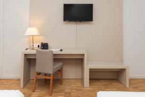 a desk with a chair and a television on a wall at Hotel Lauria in Tarragona