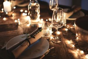 a wooden table with a plate and glasses and lights at Rixwell Elefant Hotel in Rīga