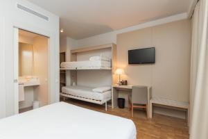 a bedroom with a bed and a desk with a monitor at Hotel Lauria in Tarragona