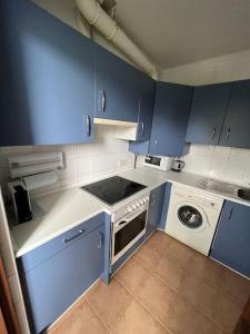 a kitchen with blue cabinets and a washing machine at Mies de Estrada in Comillas