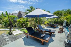 an outdoor patio with chairs and an umbrella at Bagus Dream Beach Villa Lembongan in Nusa Lembongan