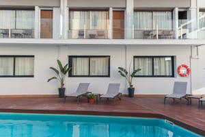 a swimming pool with chairs and a building with windows at Hotel Lauria in Tarragona