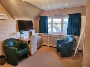 Zimmer mit 2 Stühlen, einem Schreibtisch und einem TV in der Unterkunft Hotel Pavillon Du Zoute in Knokke-Heist