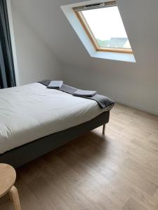 een bed in een witte kamer met een raam bij Maison Jardin De La Baie in Douarnenez