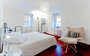 ein weißes Schlafzimmer mit einem Bett und einem Stuhl in der Unterkunft Presidental Suite Apartment by Livingdowntown in Zürich