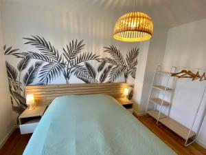 Schlafzimmer mit einem Bett und einem Wandbild von Palmen in der Unterkunft Naturescence in Saint-Martin-Boulogne
