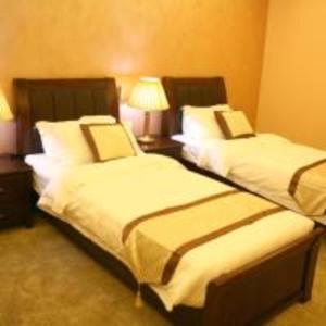 two beds in a hotel room with two lamps at Seven Wonders Hotel in Wadi Musa