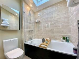 a bathroom with a tub and a toilet and a sink at Chic Clifton Home – inviting décor & outdoor space in Bristol
