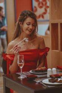 Eine Frau in einem roten Kleid, die Essen an einem Tisch isst. in der Unterkunft Astoria Hotel All Inclusive & Private Beach in Goldstrand