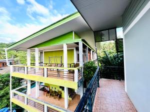 a house with a large deck with yellow and green at Blue Wave House in Koh Tao