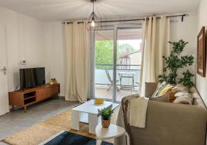 sala de estar con sofá y TV en Confortable T2 pour 4 voyageurs, parking privé et terrasse, en Toulouse