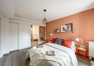 1 dormitorio con 1 cama grande y pared de color naranja en Confortable T2 pour 4 voyageurs, parking privé et terrasse, en Toulouse