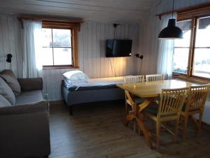 a living room with a table and a bed at Fyrklöverns Stugby in Rättvik