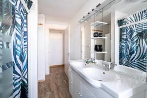 uma casa de banho branca com um lavatório e um espelho em Appartement 10 pers à 50m plage em Barbâtre